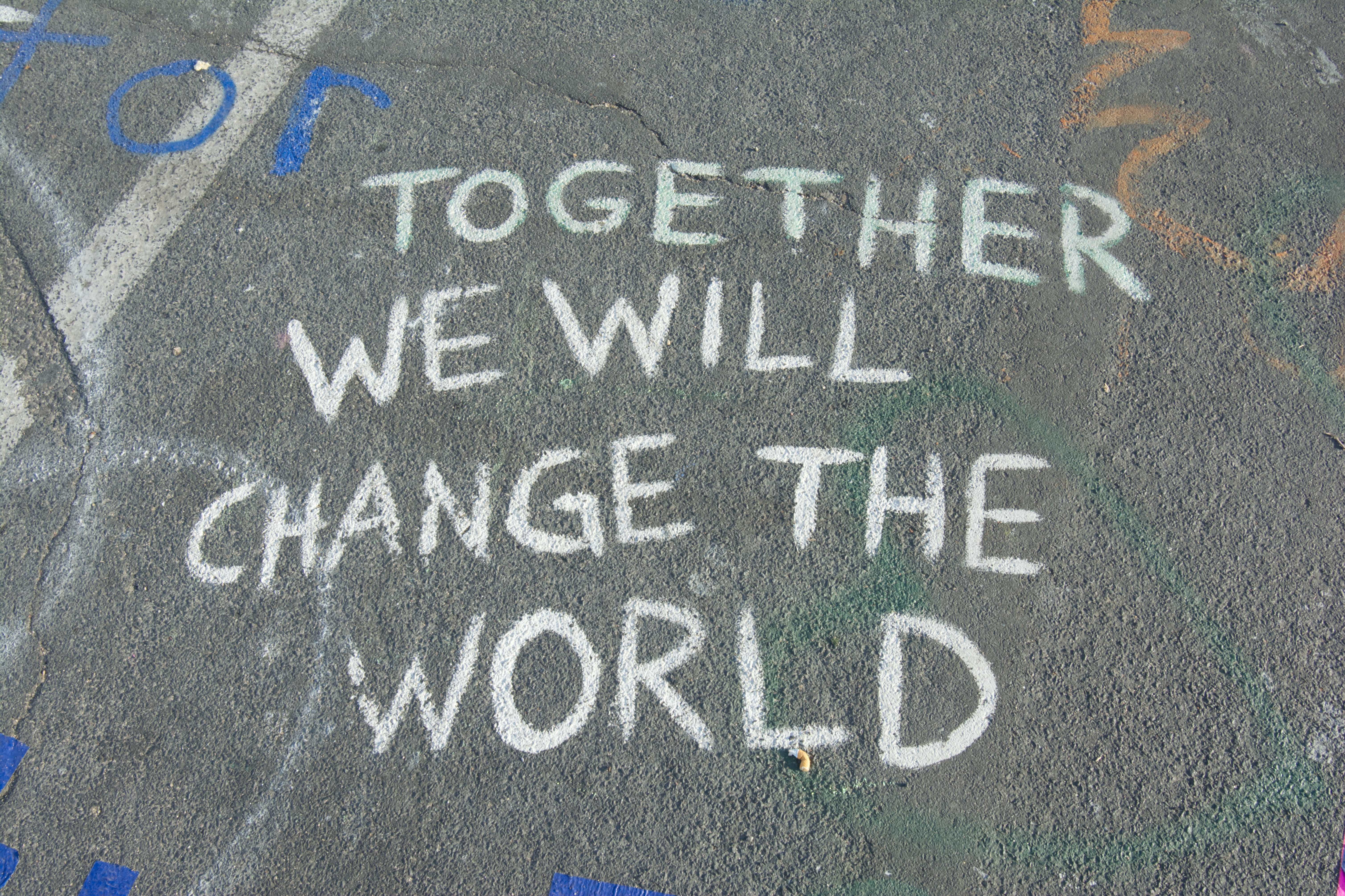 Chalk writing on pavement saying Together we will change the world