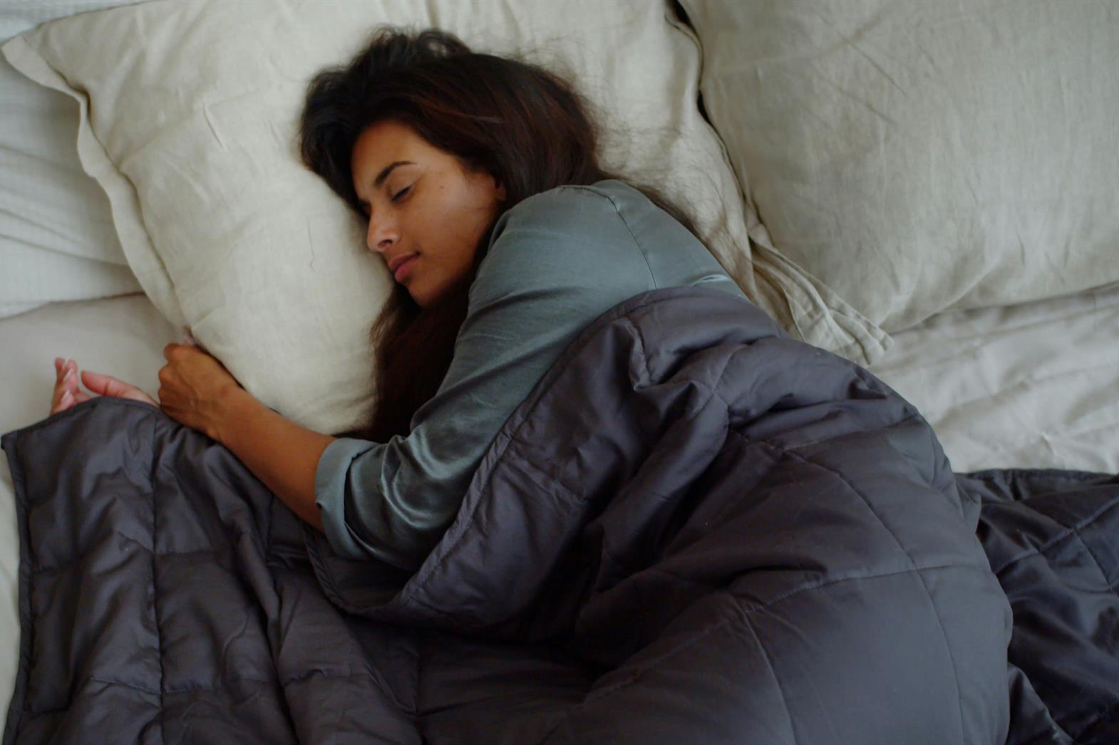 a woman sleeping on a bed with a blue blanket