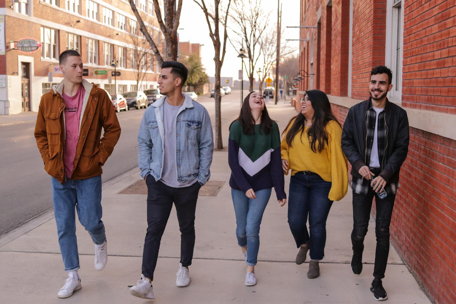 A group of people walking down a sidewalk and laughing
