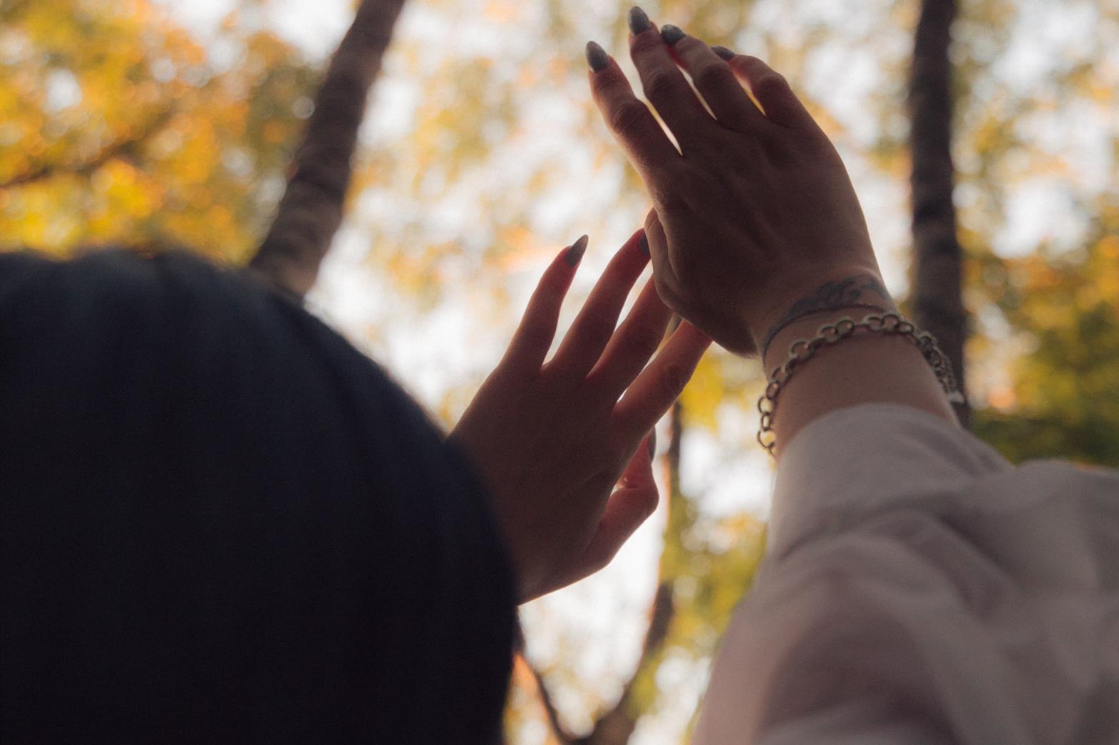A woman holding her arms up under trees in autum