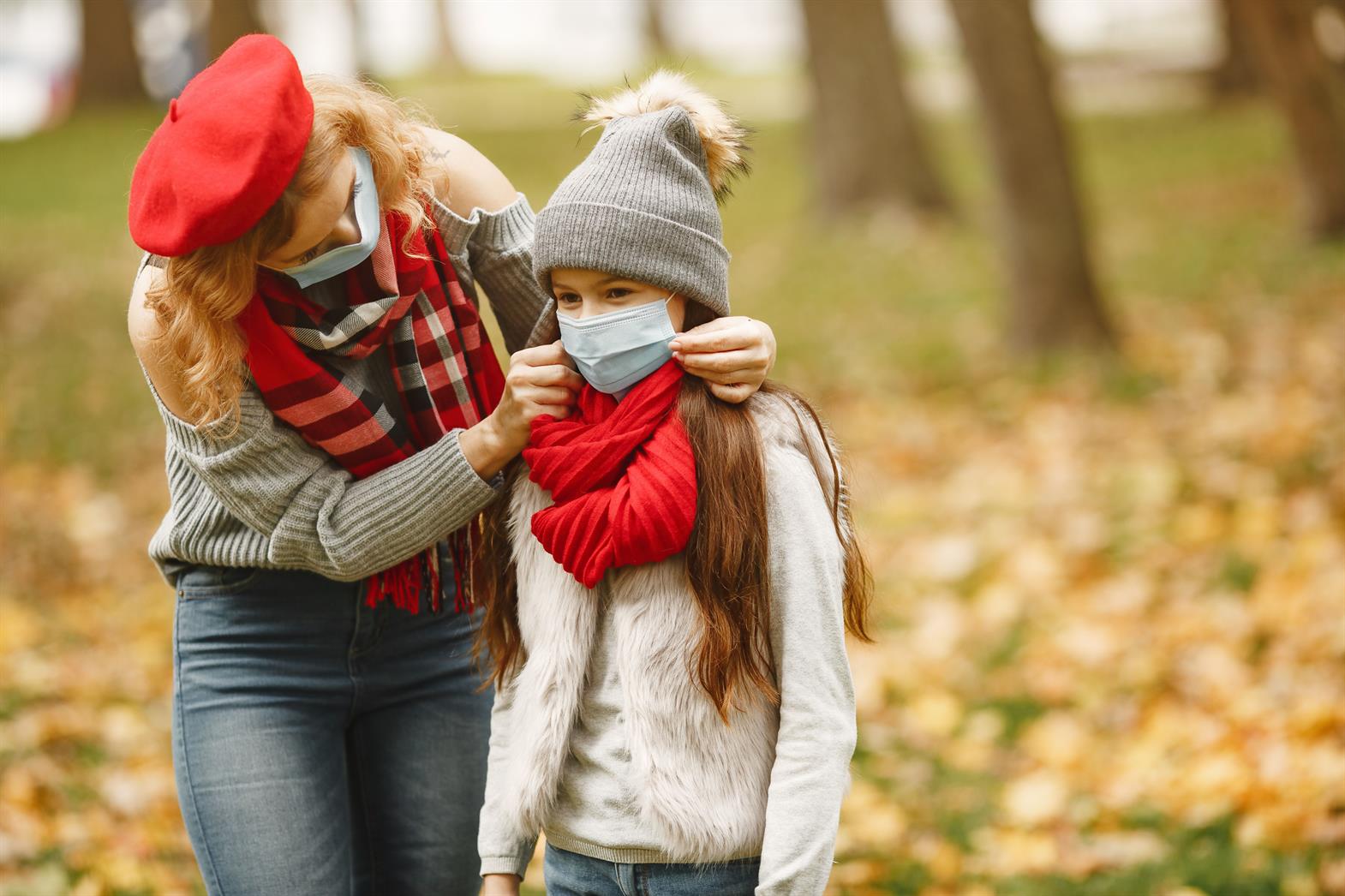 Une mère aide sa fille à ajuster son masque dans un parc