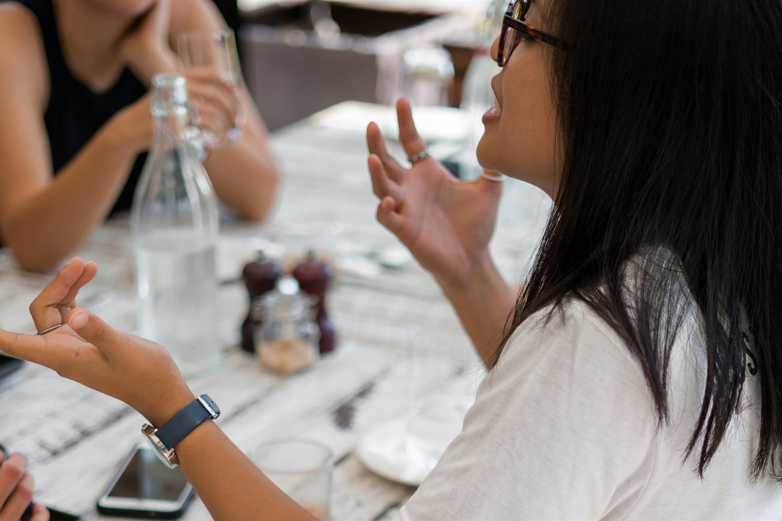 A woman gesturing with her hands while speaking to friends