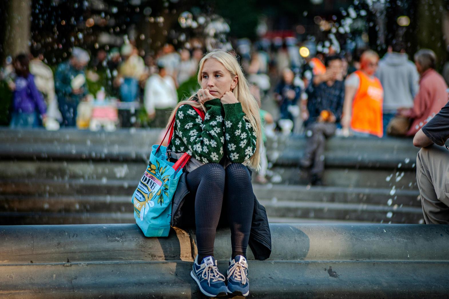 A thoughtful woman sitting by a fountain in a park