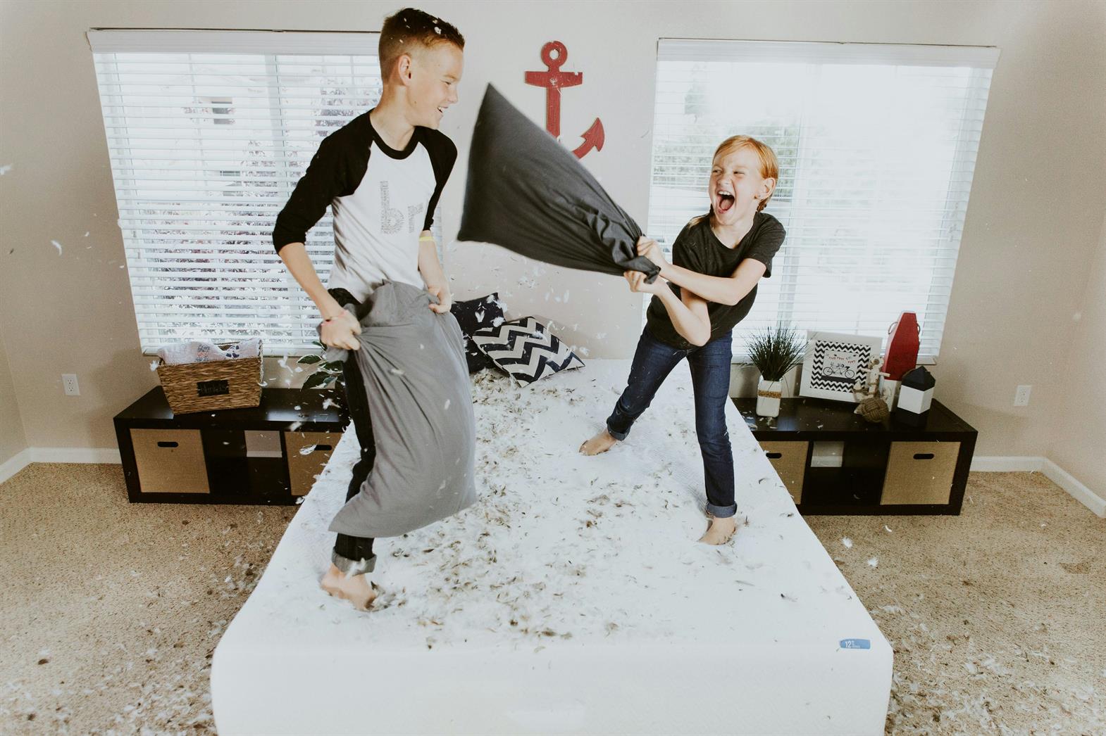 Two kids having a pillow fight on a bed