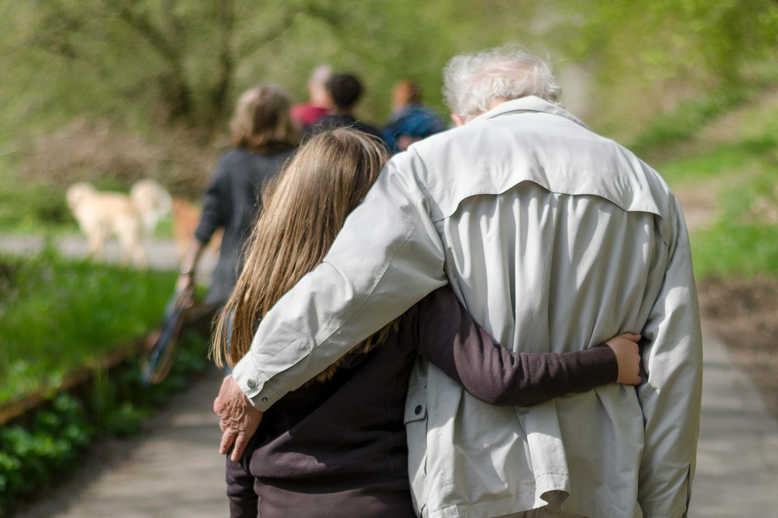 A grandfather and his granddaughter walking together in a park