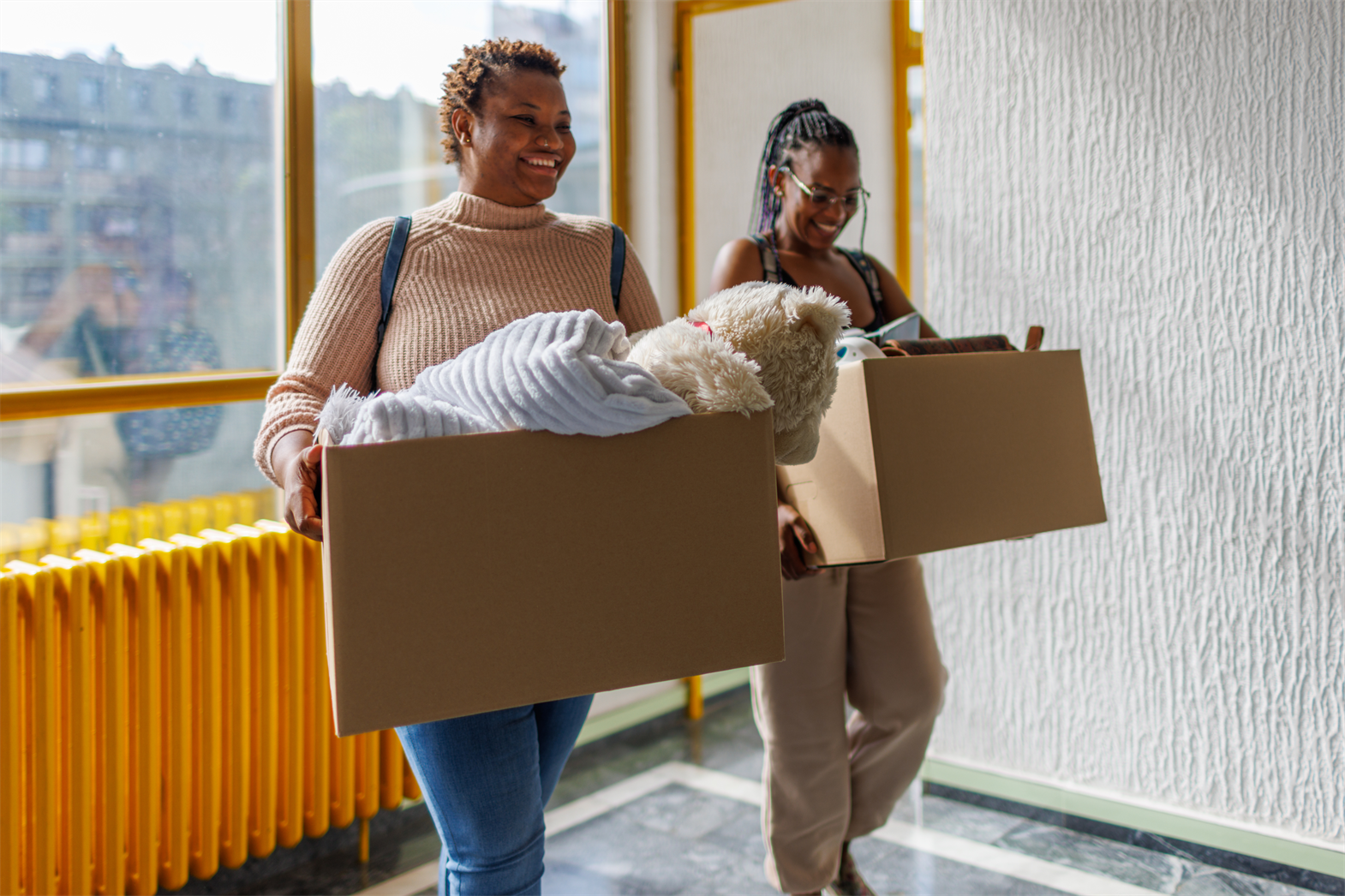 An person and their parent carrying boxes on moving day
