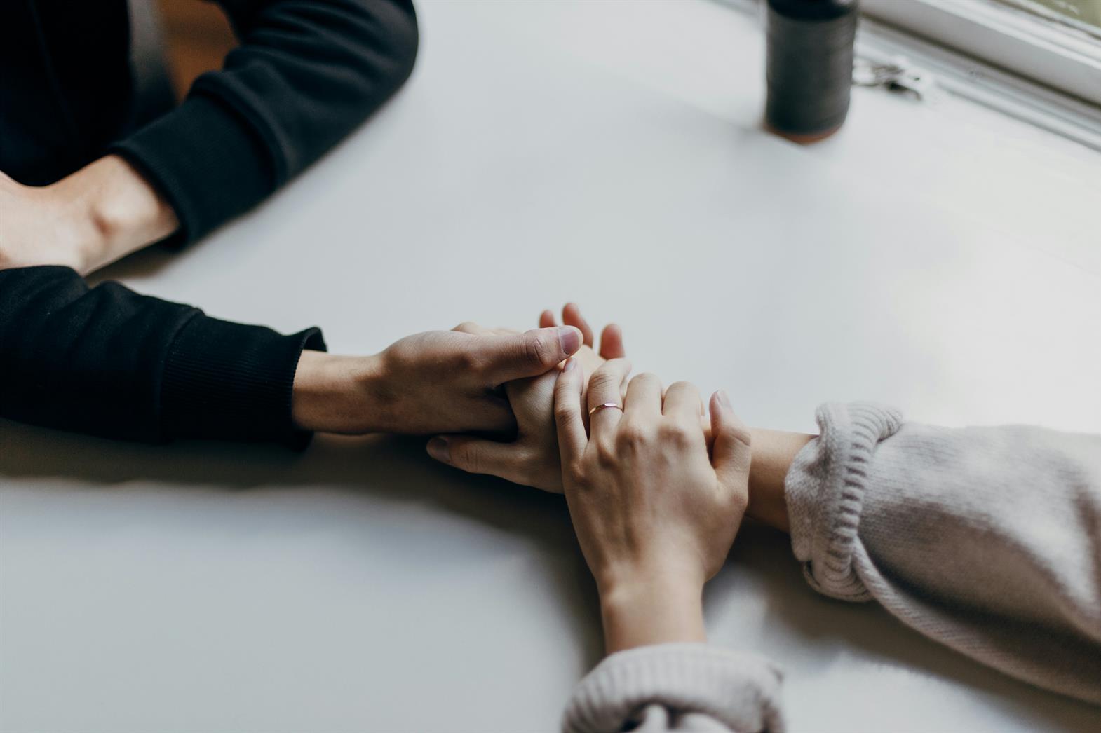 two people holding hands across a table 