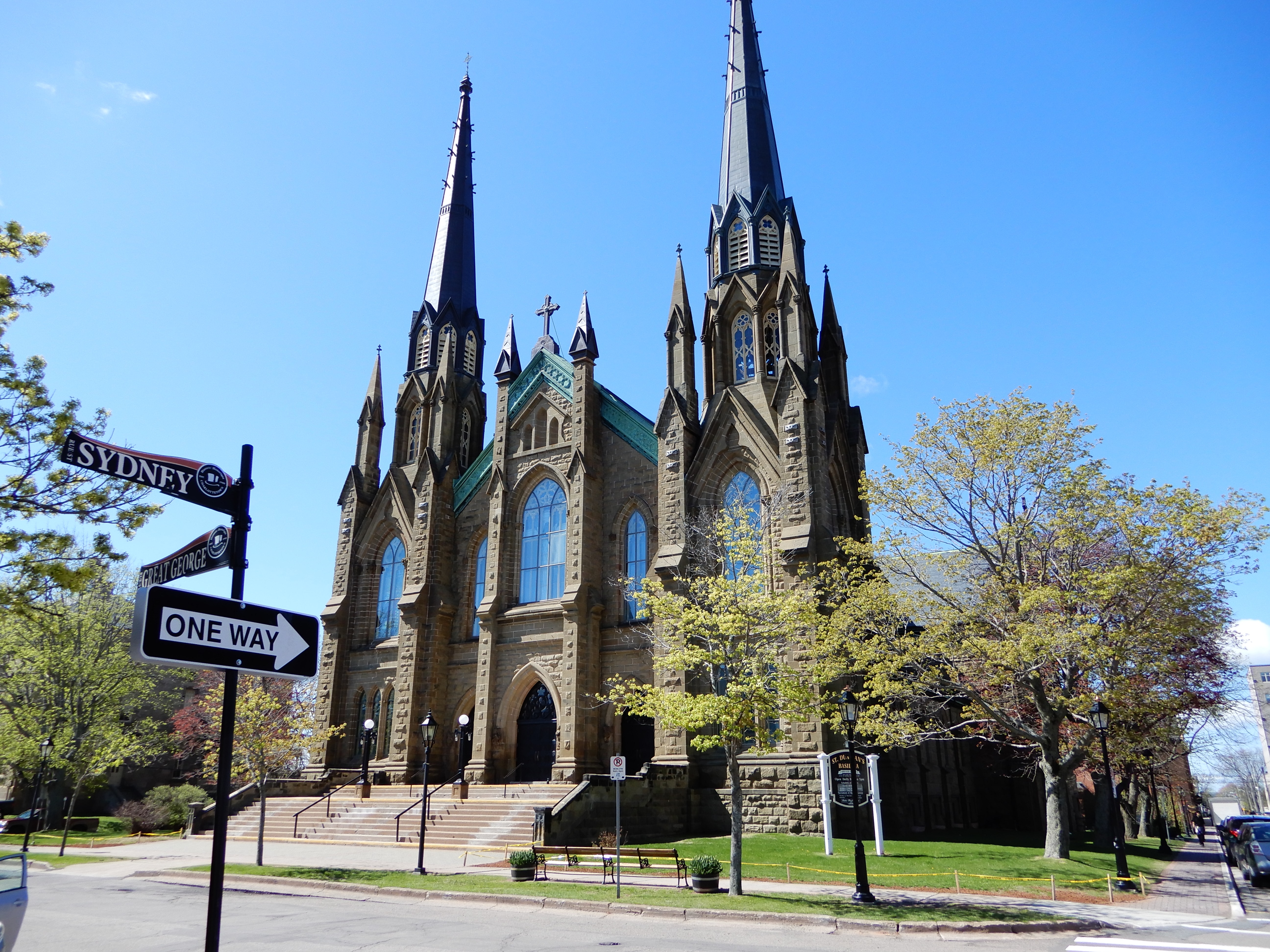 A stone church on a spring day in Charlottetown PEI. Blue skies in the background. A one was sign post in the foreground.