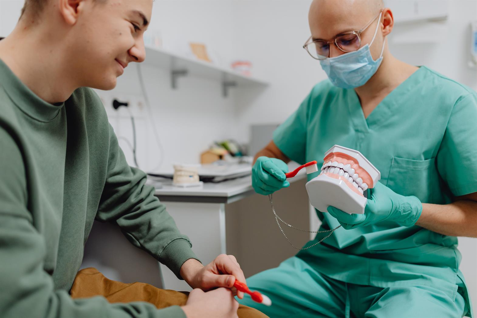 A dentist demonstrates proper dental hygiene to a patient using a model