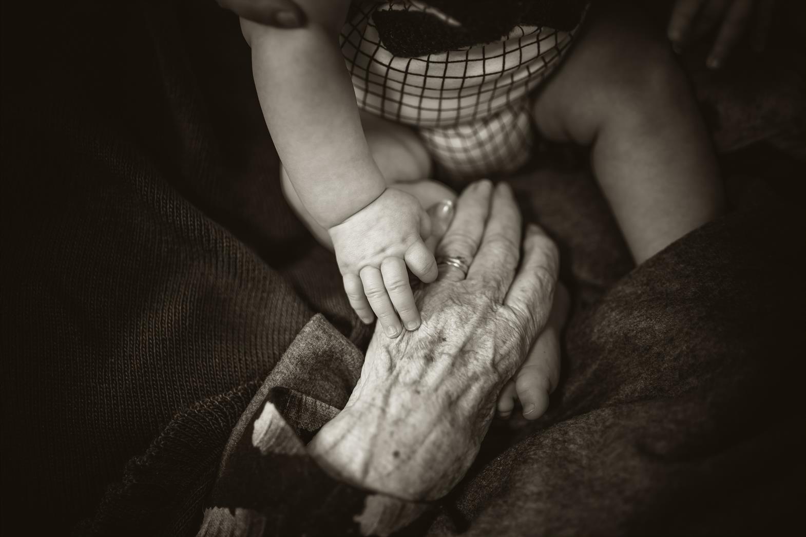 Elderly hand holding a baby