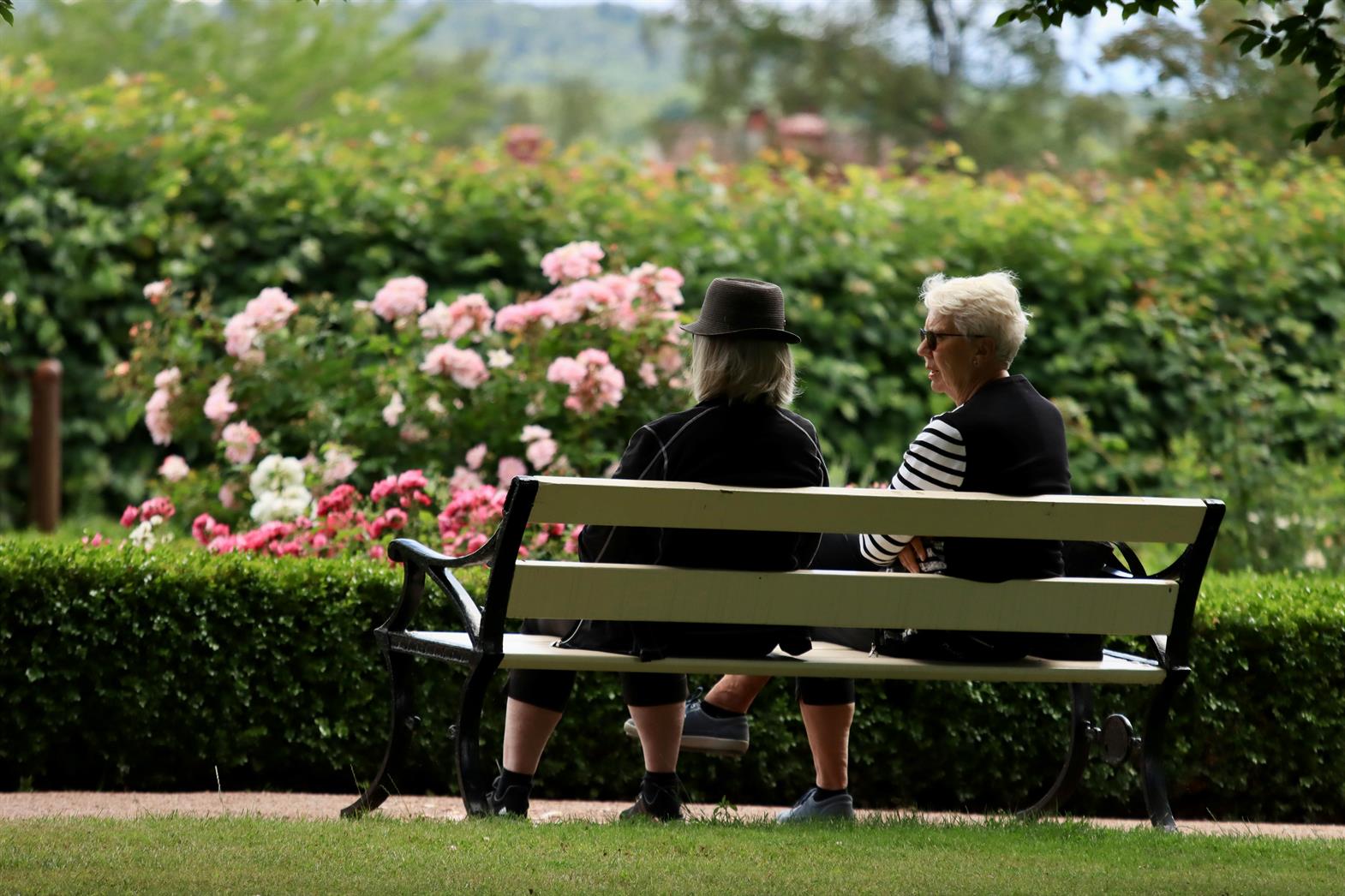 Deux personnes assises sur un banc dans un jardin