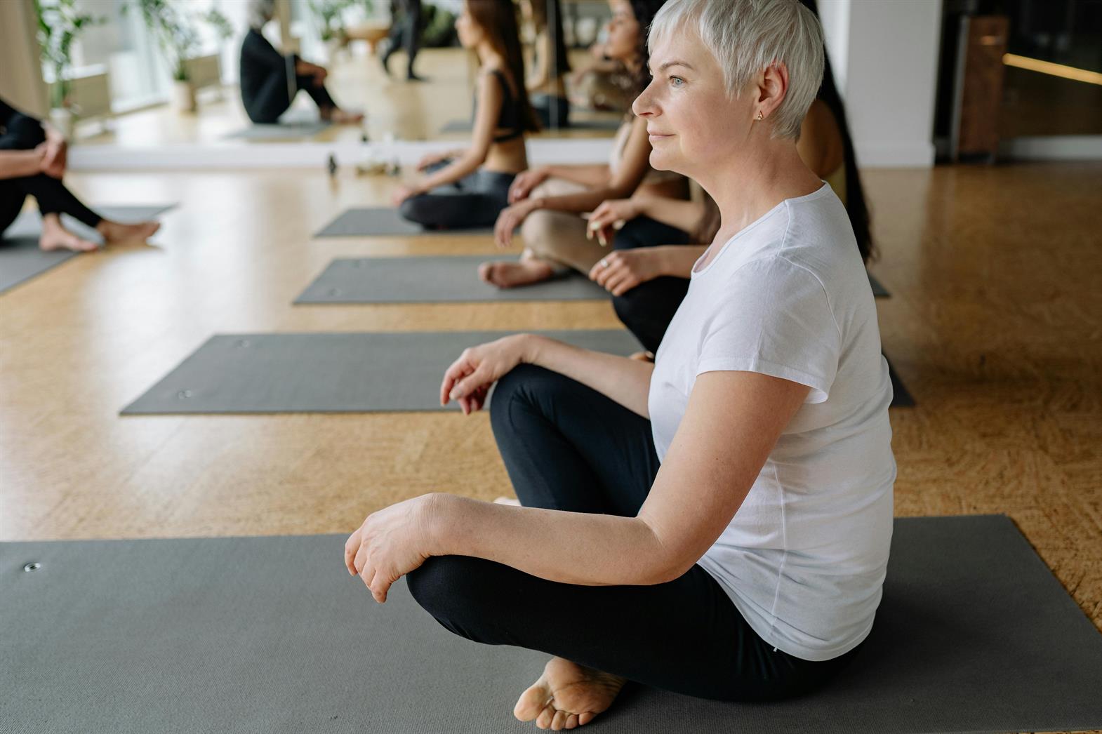 A senior woman practicing meditation a yoga class