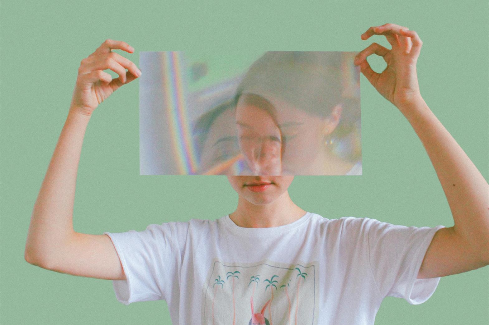 A woman holding a reflective sheet in front of her face like a mask