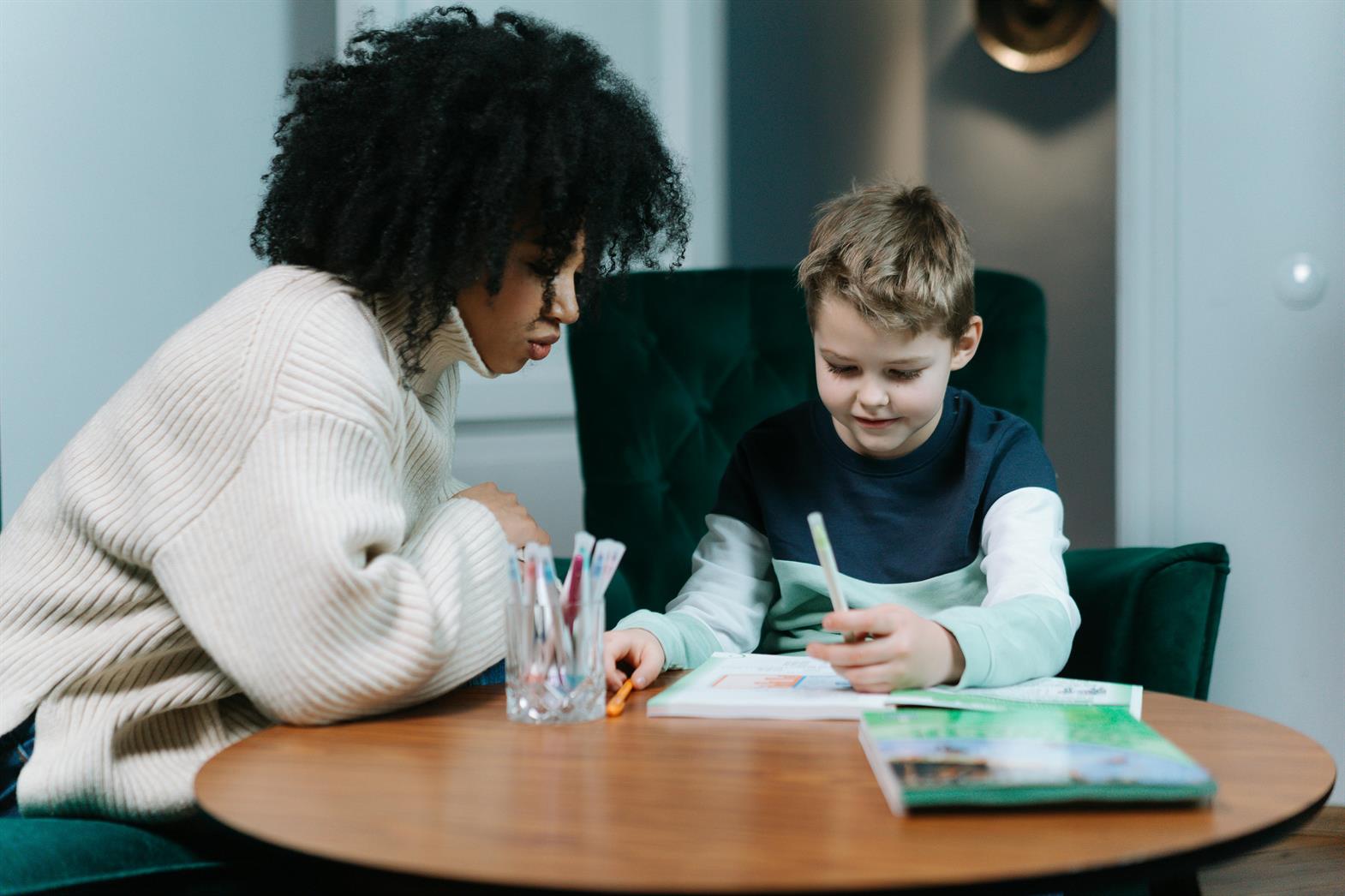 Une femme qui aide un enfant à faire ses devoirs