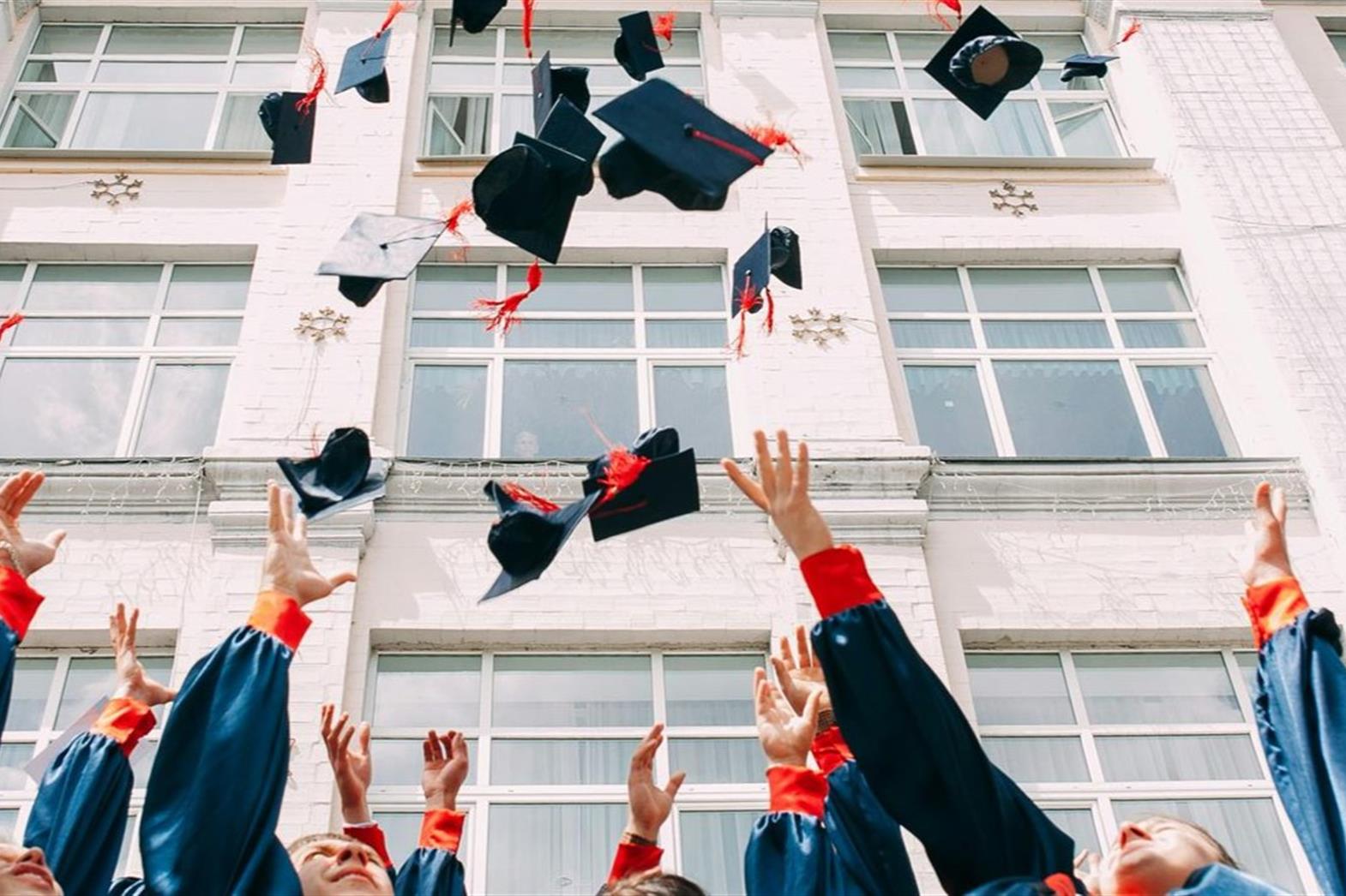 groupe d'étudiants fraîchement diplômés jetant leur chapeau académique en l'air