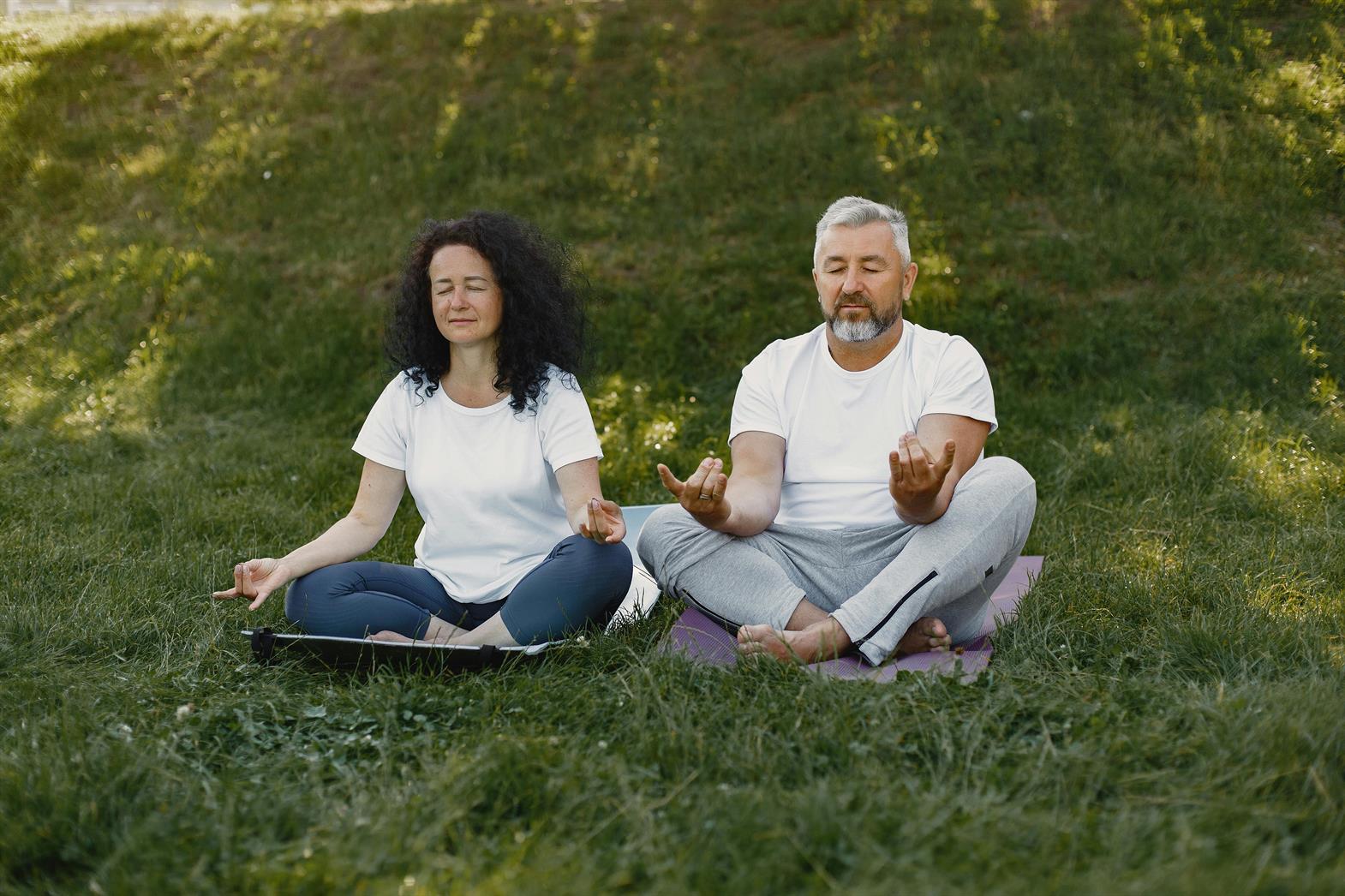 Un couple de personnes âgées médite ensemble en plein air sur des tapis de yoga