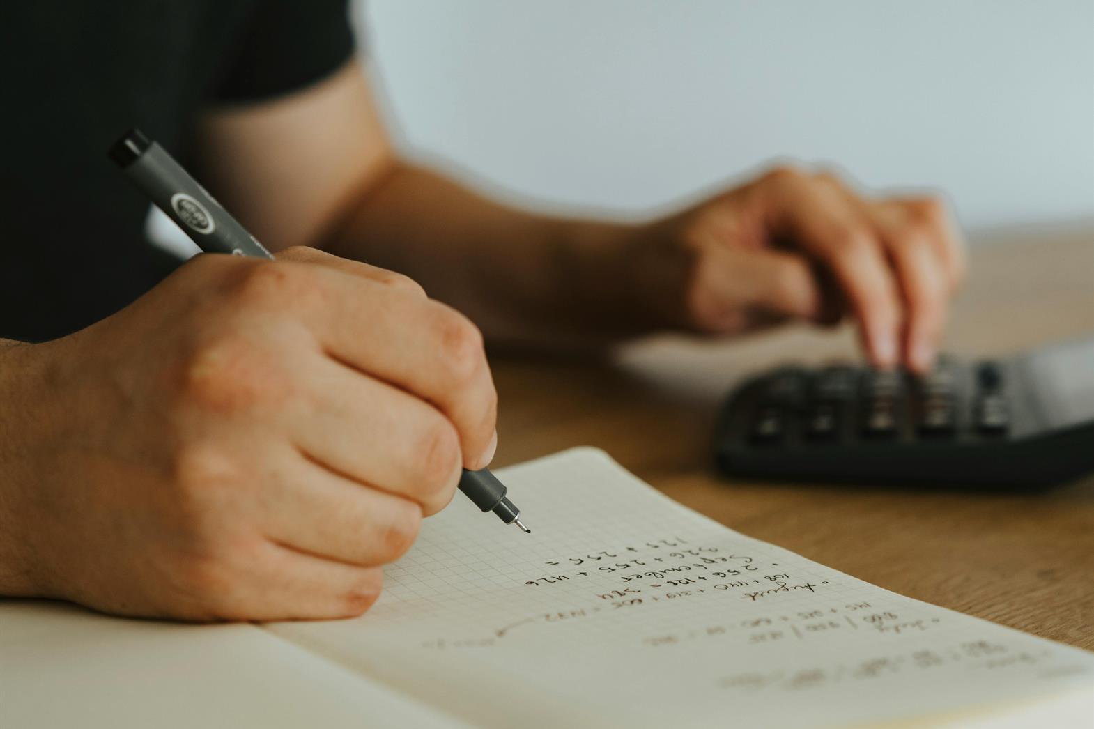 A person doing math with a notebook and calculator