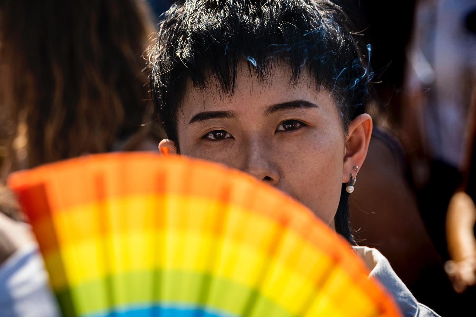 A person holding a rainbow fan
