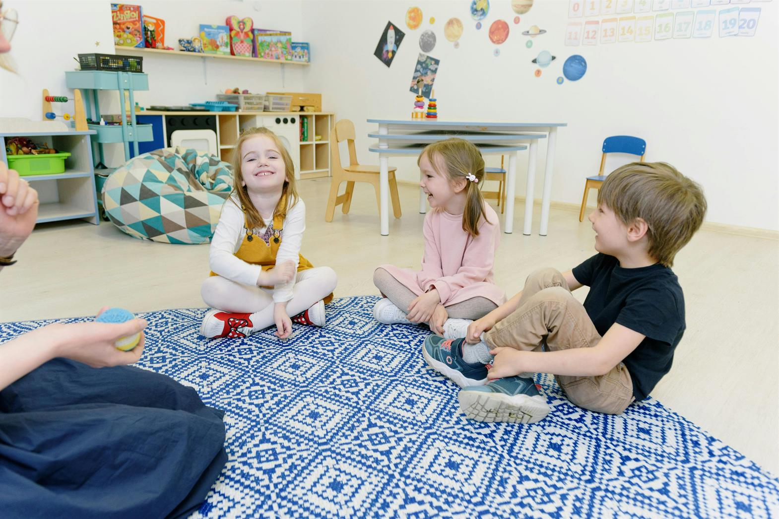 three children sitting on a rug in a classroom