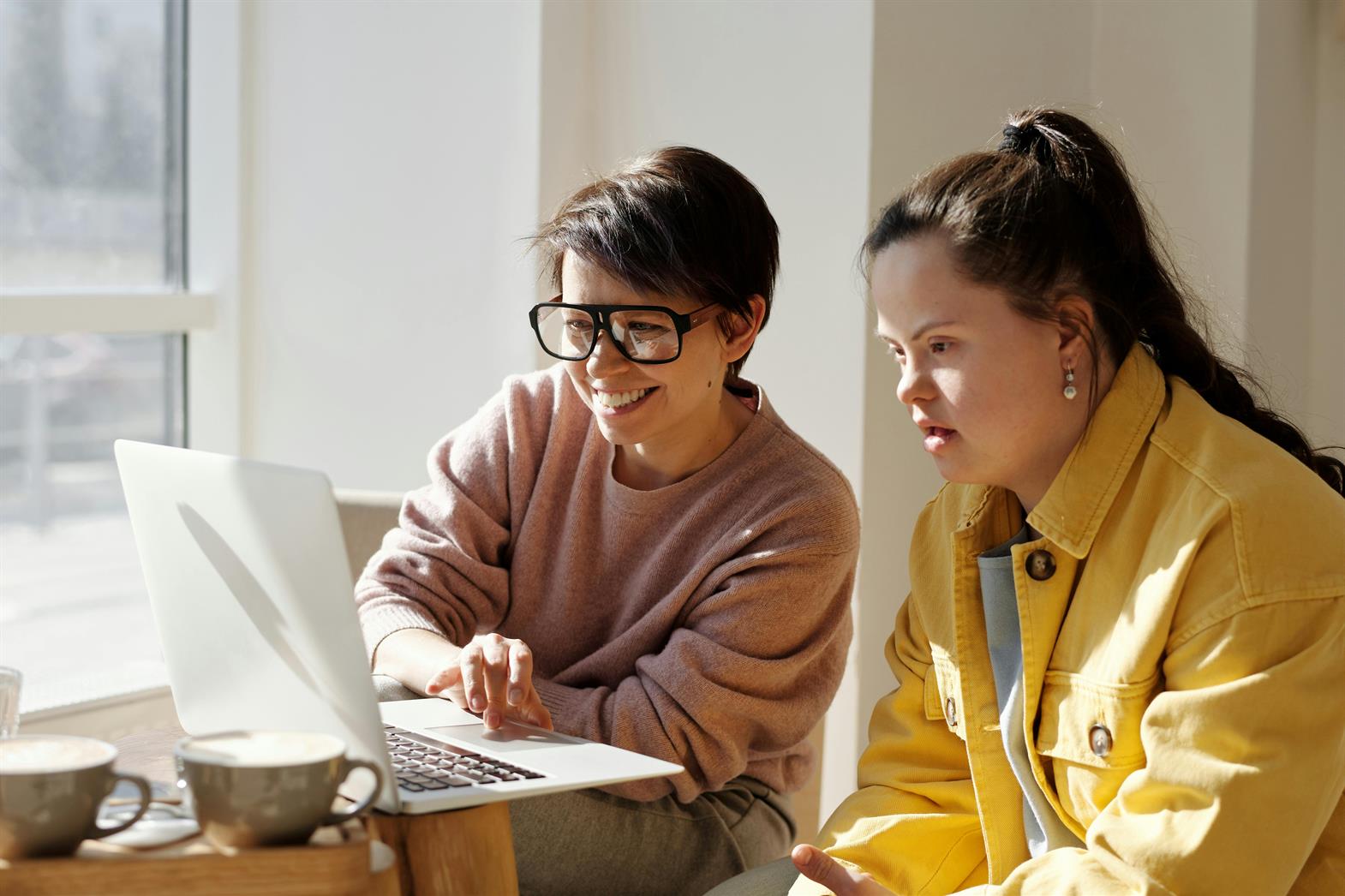 Two Women Using a Laptop Near a Window