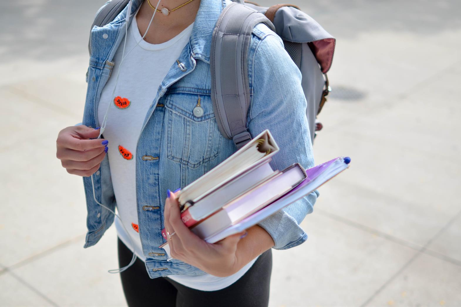 Close up photo of a female college student carrying textbooks