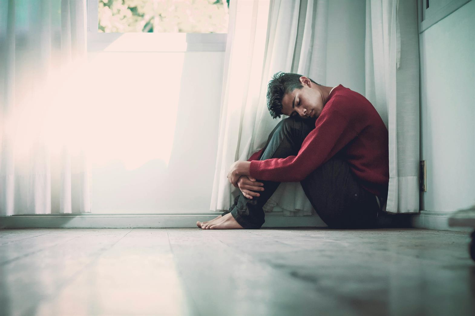 A person sitting on the floor next to a window