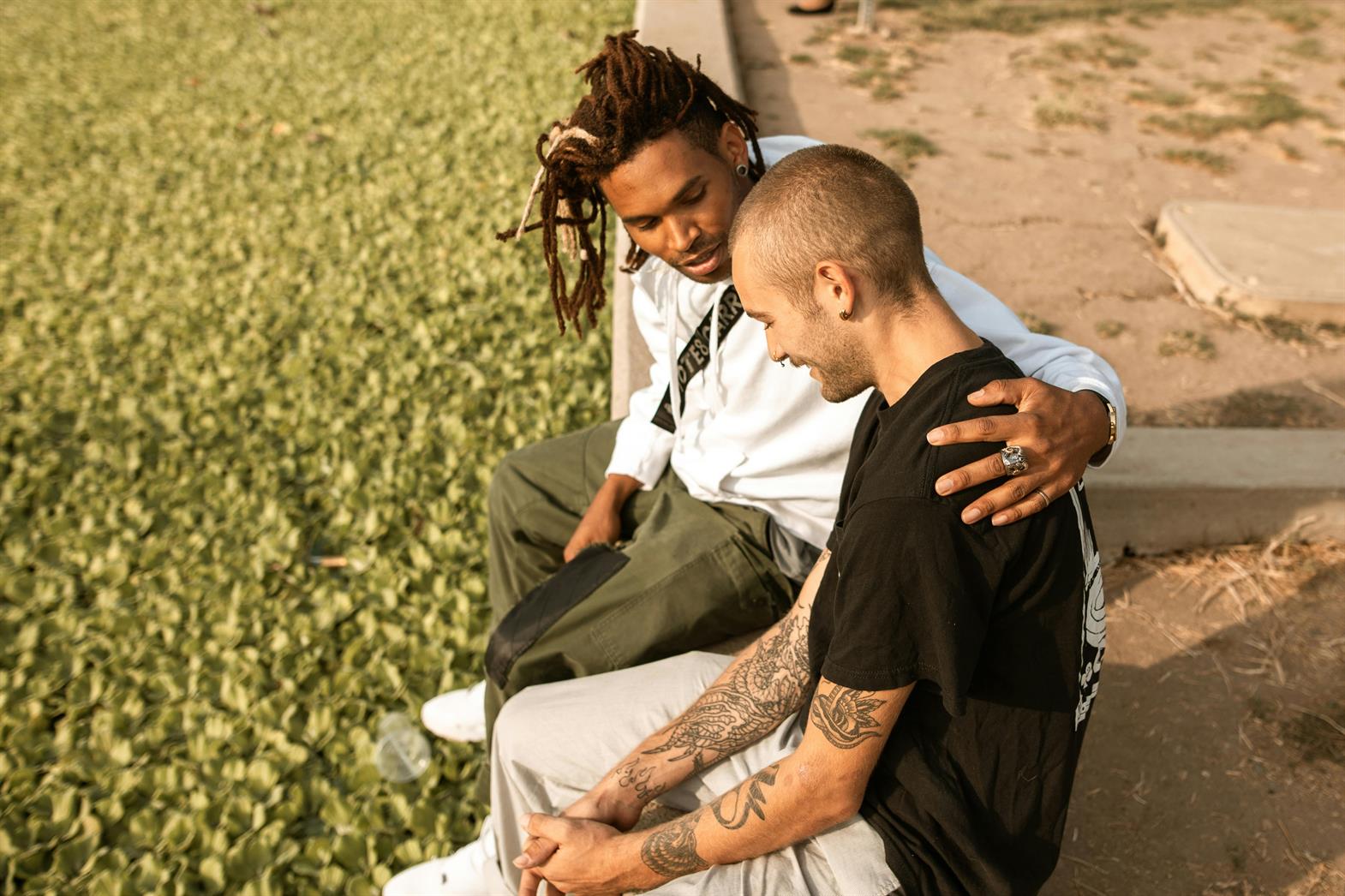 A man comforting a friend in a park 