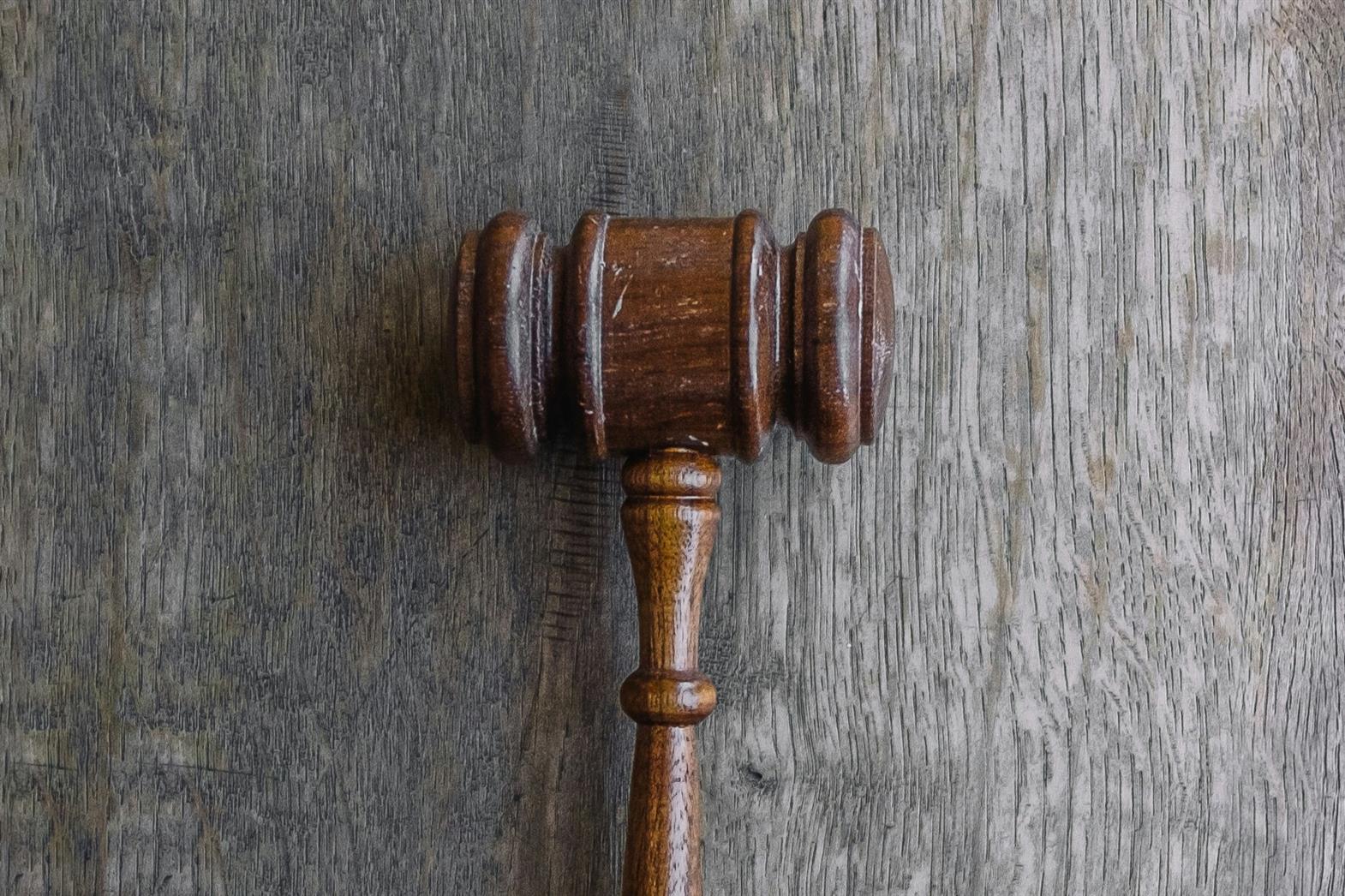 Un marteau de juge brun posé sur une surface en bois gris