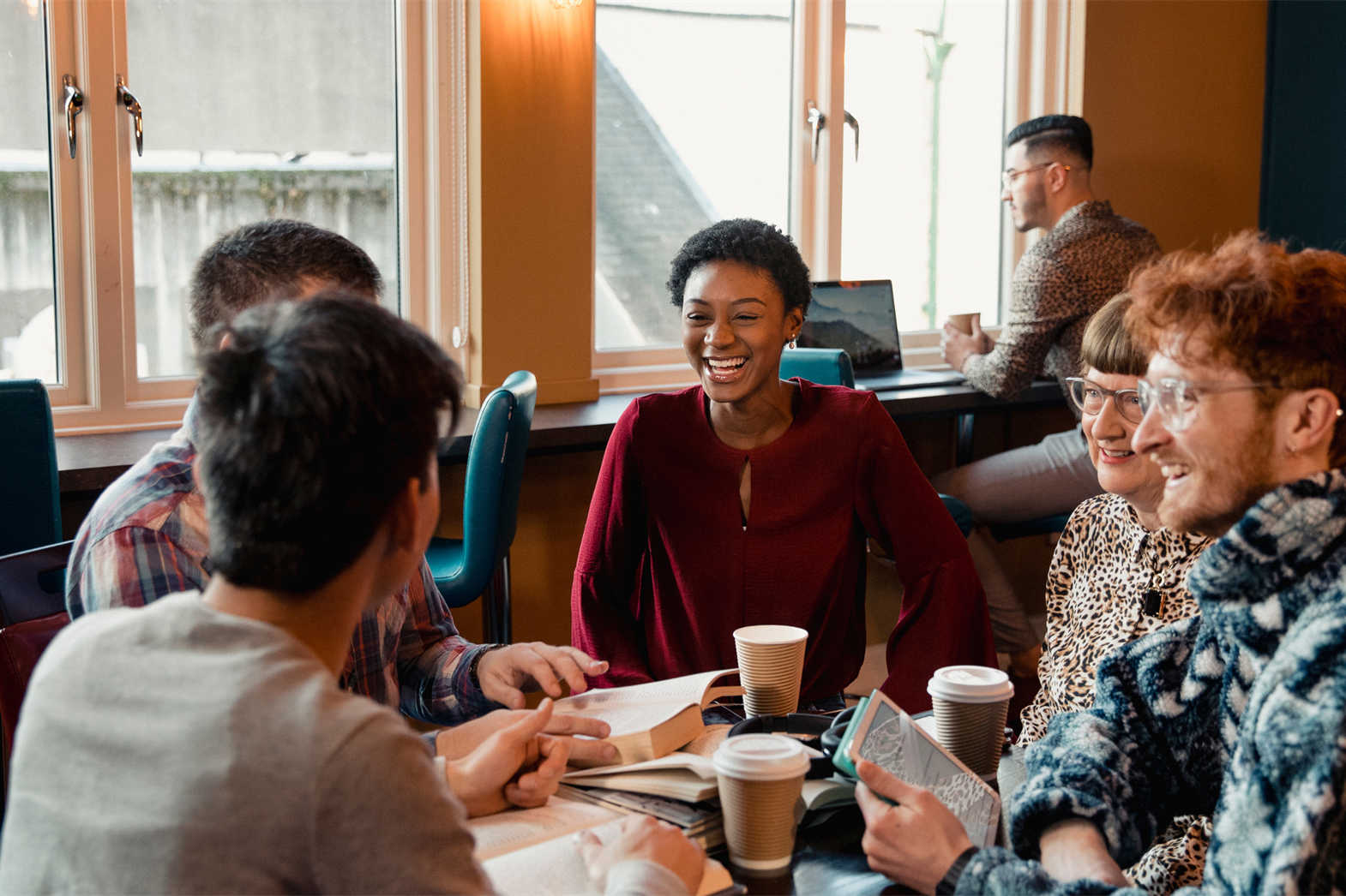 Un groupe diversifié de personnes se réunissant dans un café pour un club de lecture