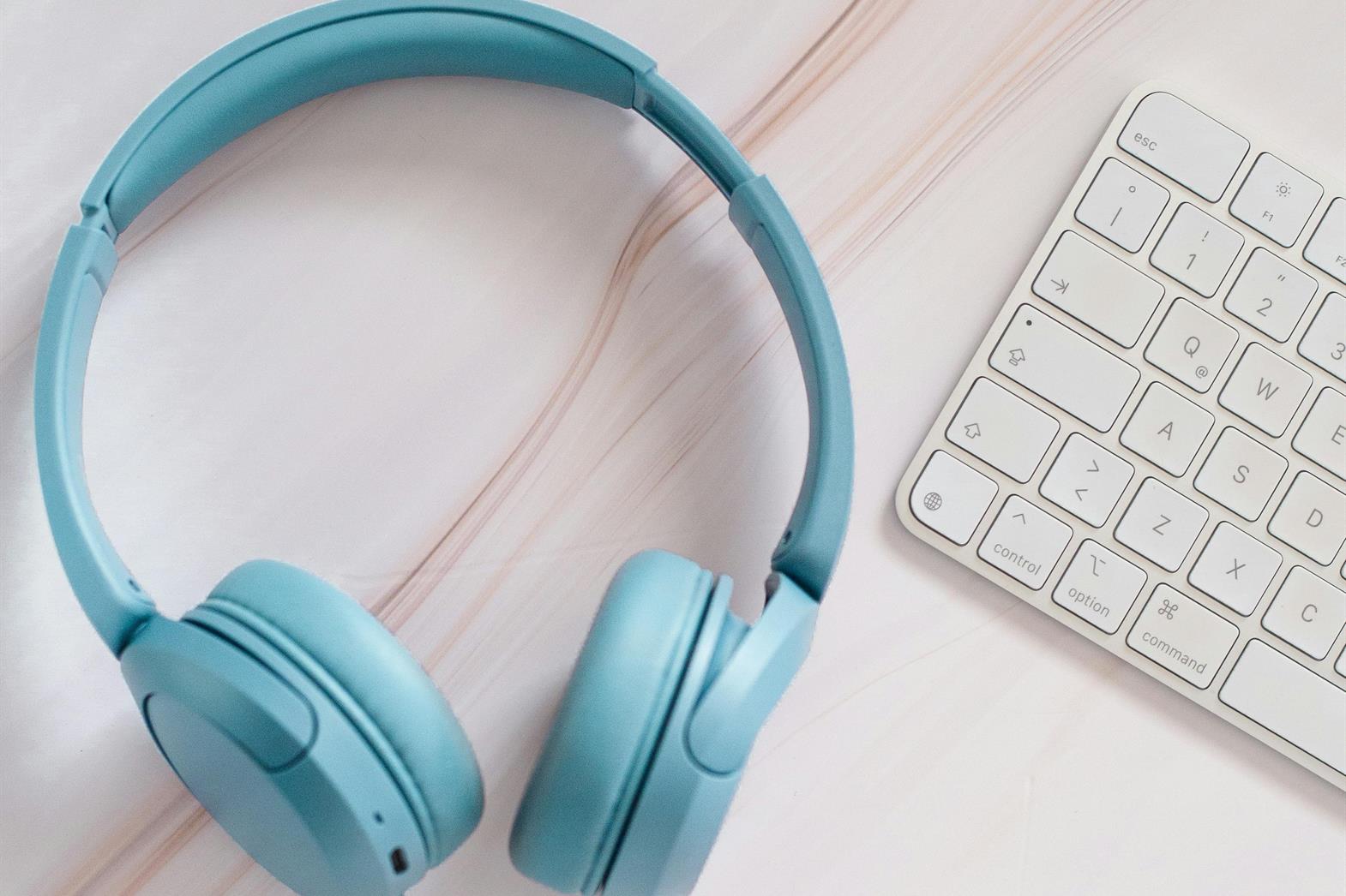Blue headphones next to a white keyboard