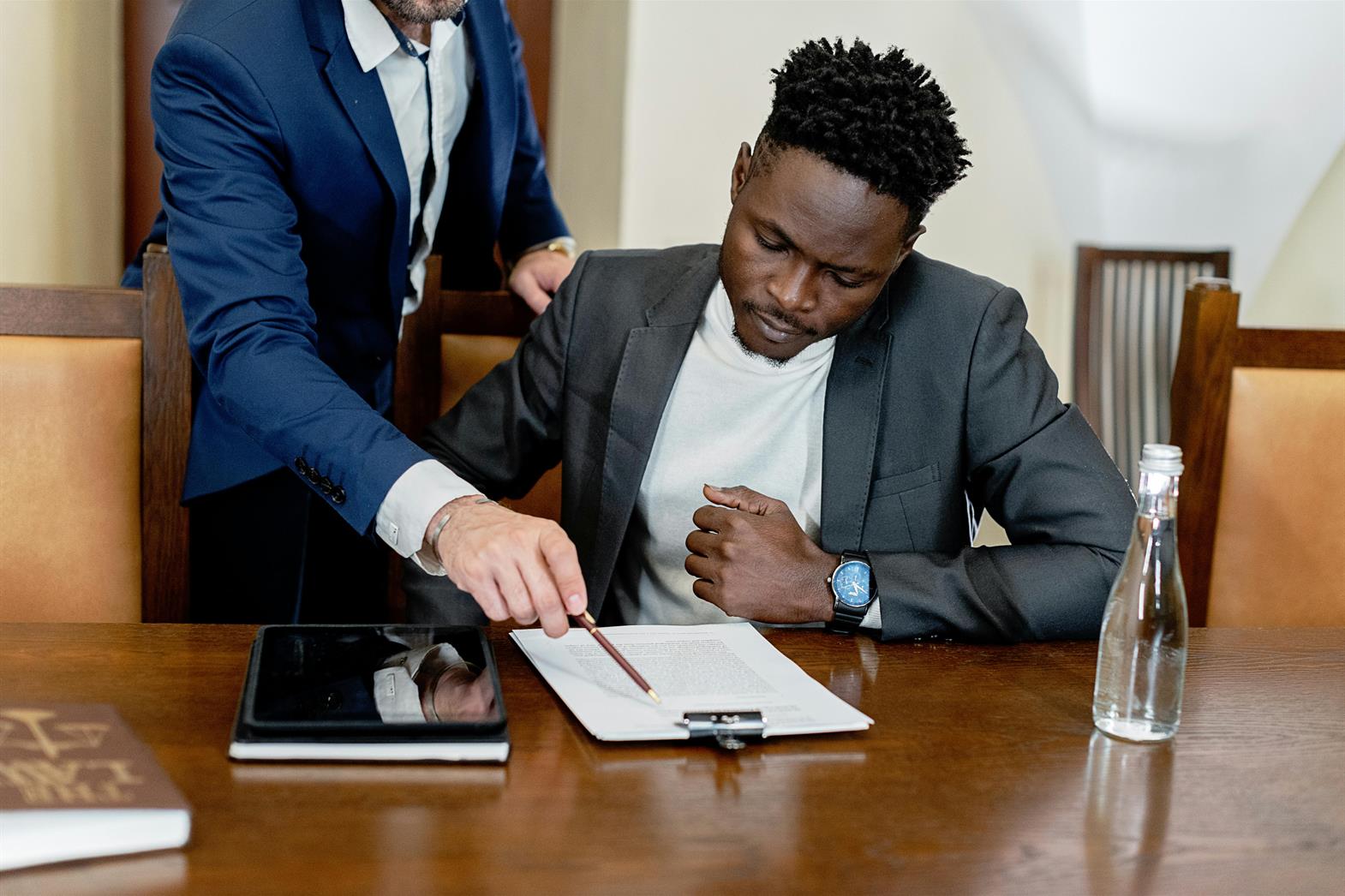 A Man in Gray Suit Looking at a Document on a Table