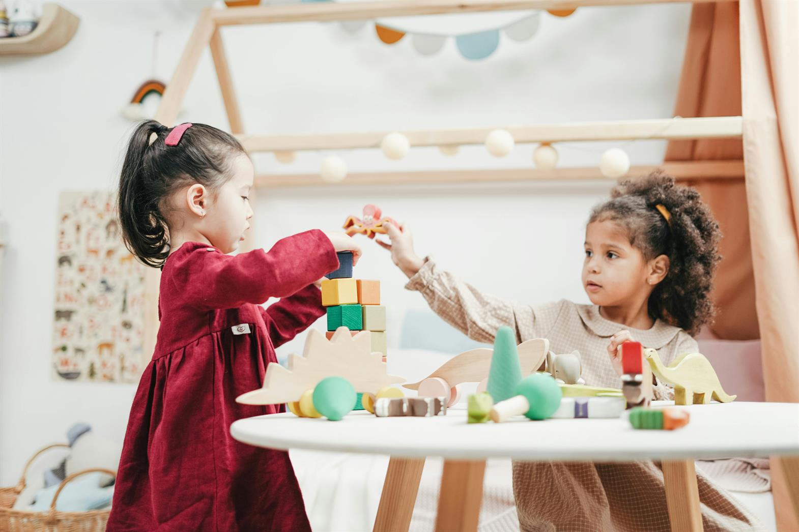Two young girls playing with toy blocks at a table