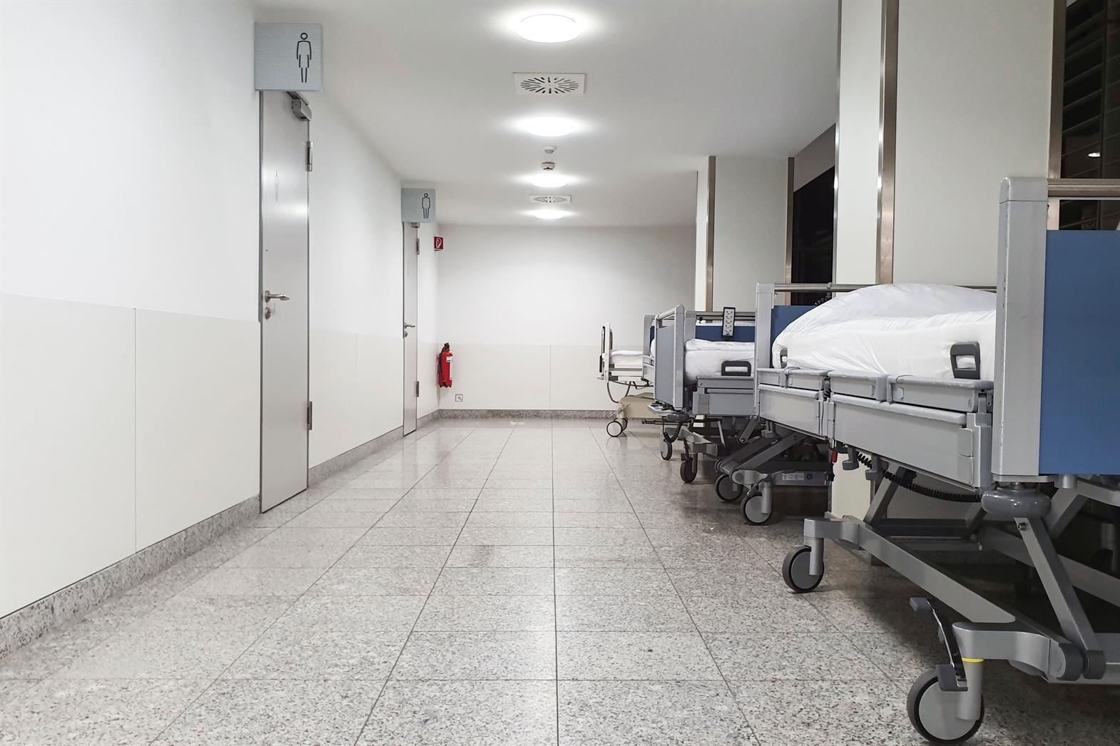 Couloir d'hôpital moderne avec des lits d'hôpital vides et un environnement stérile.
