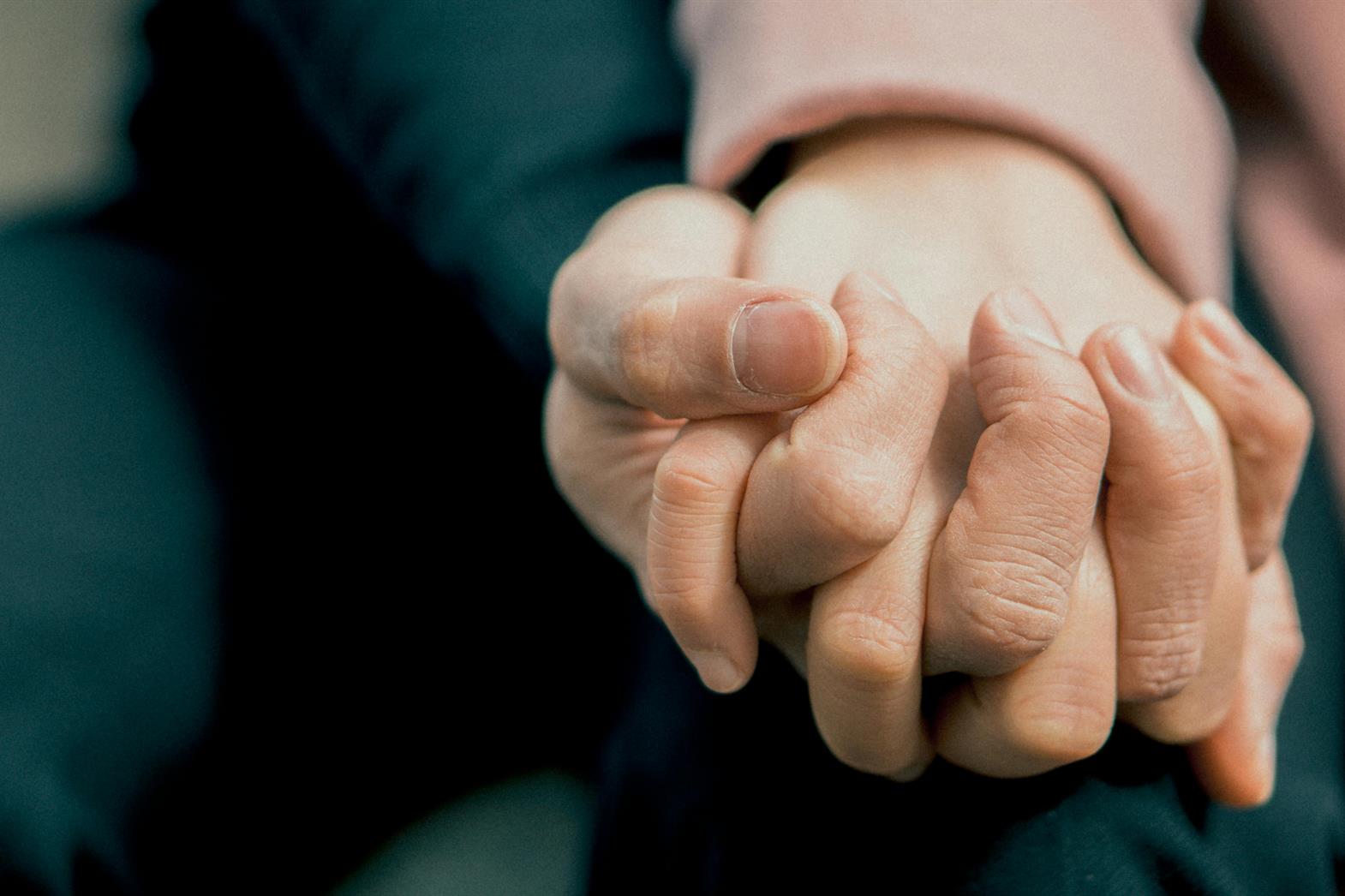 Close up photo of two people holding hands