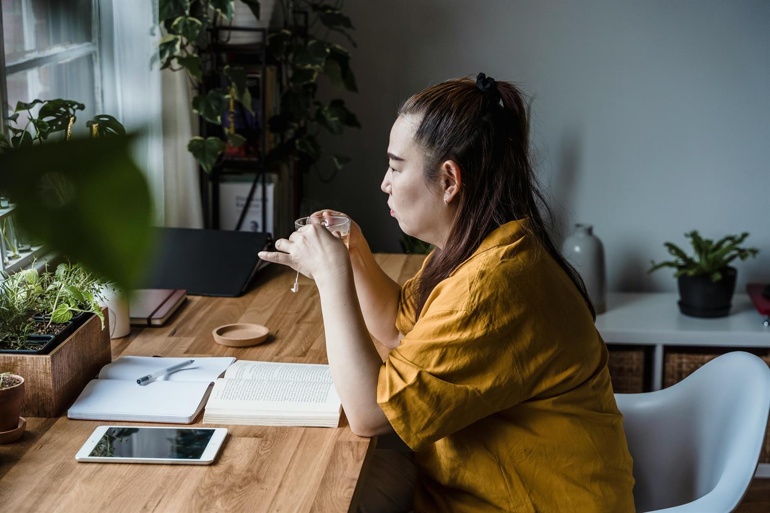 Une femme tenant une tasse de thé à un bureau