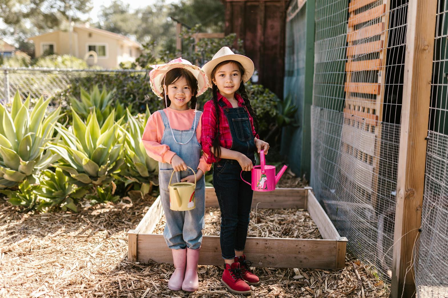 Deux filles tenant des arrosoirs pendant qu'elles jardinent
