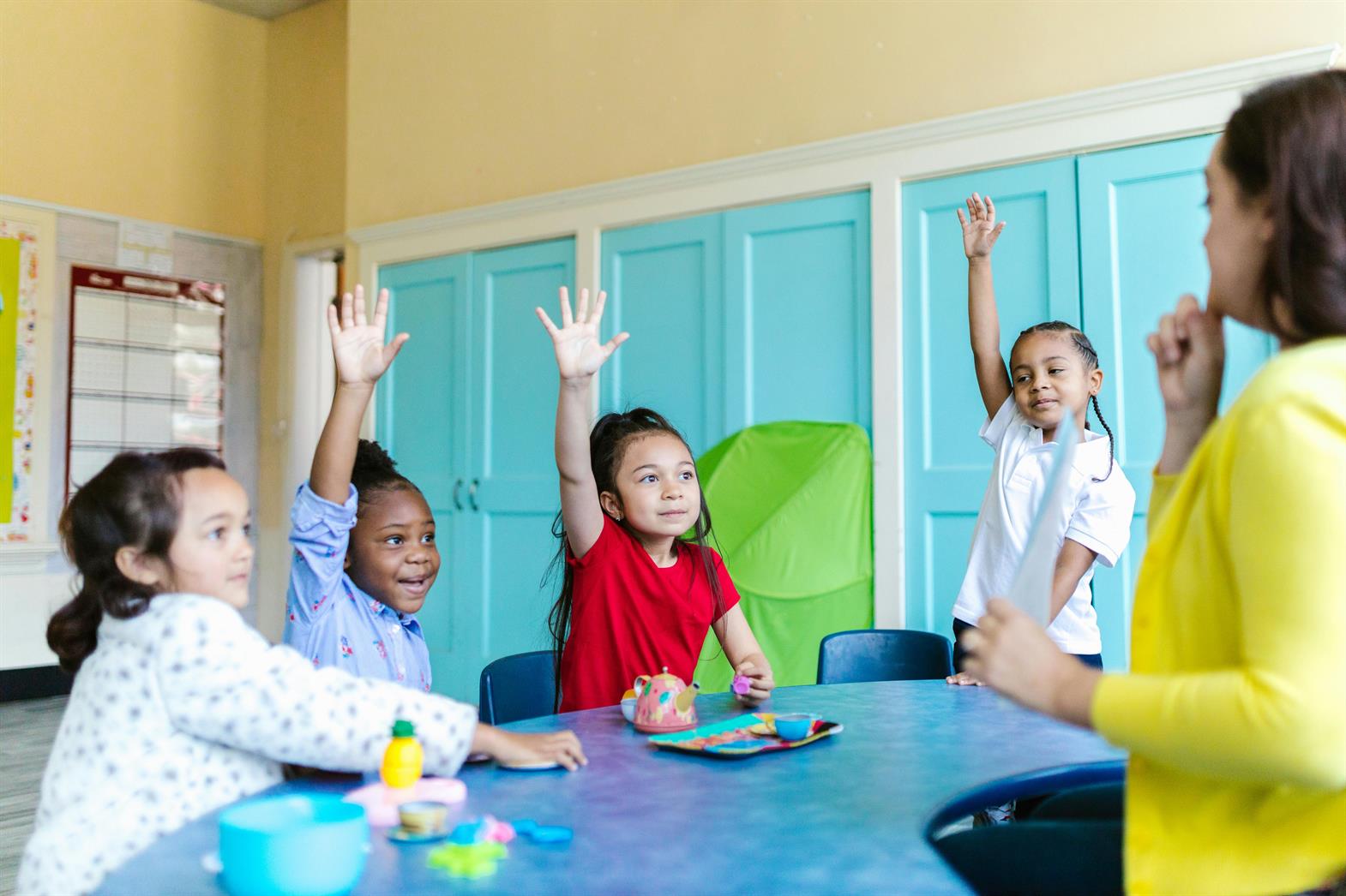 A group of children raising their hands at school