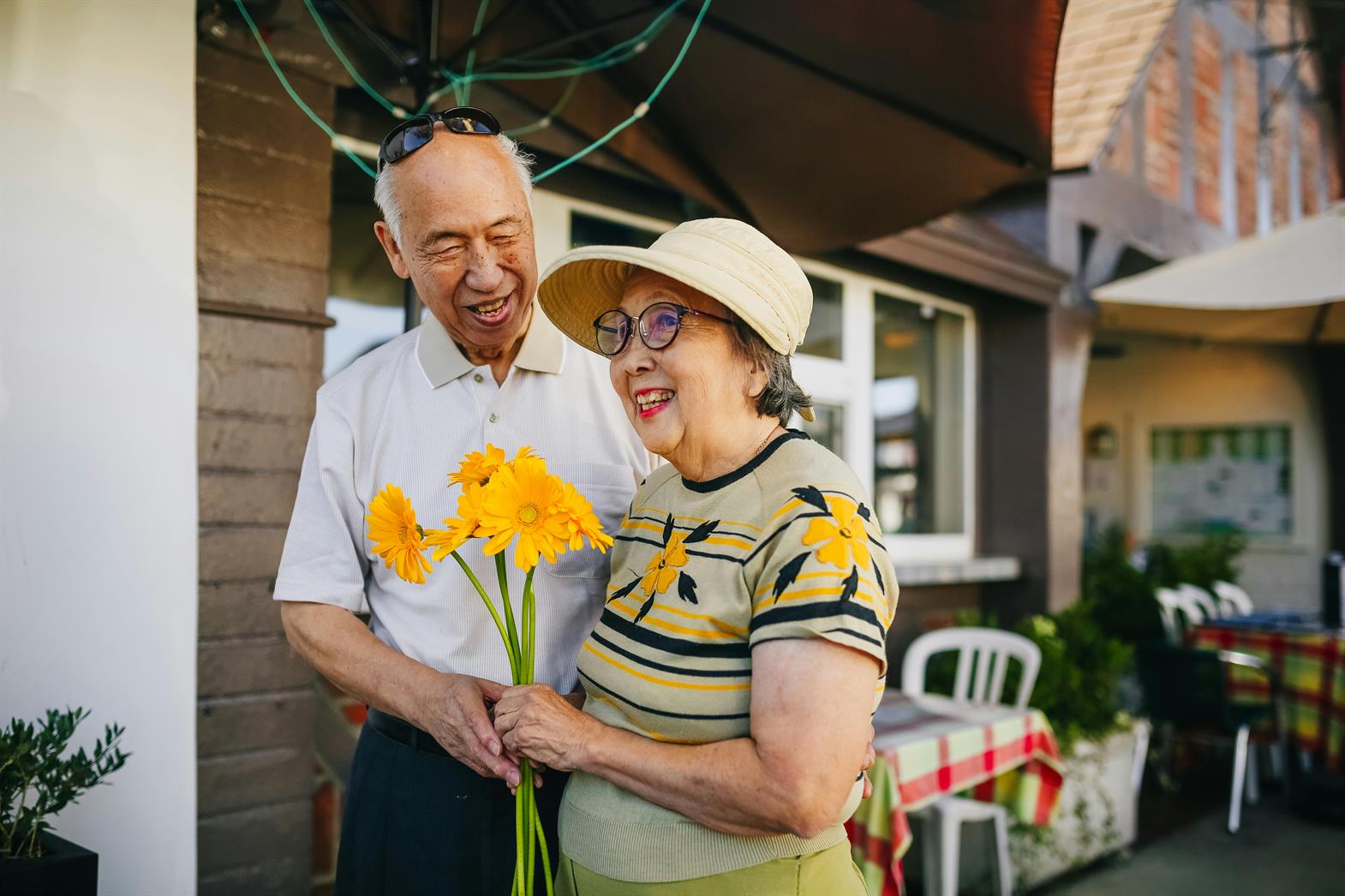A senior couple holding yellow flowers