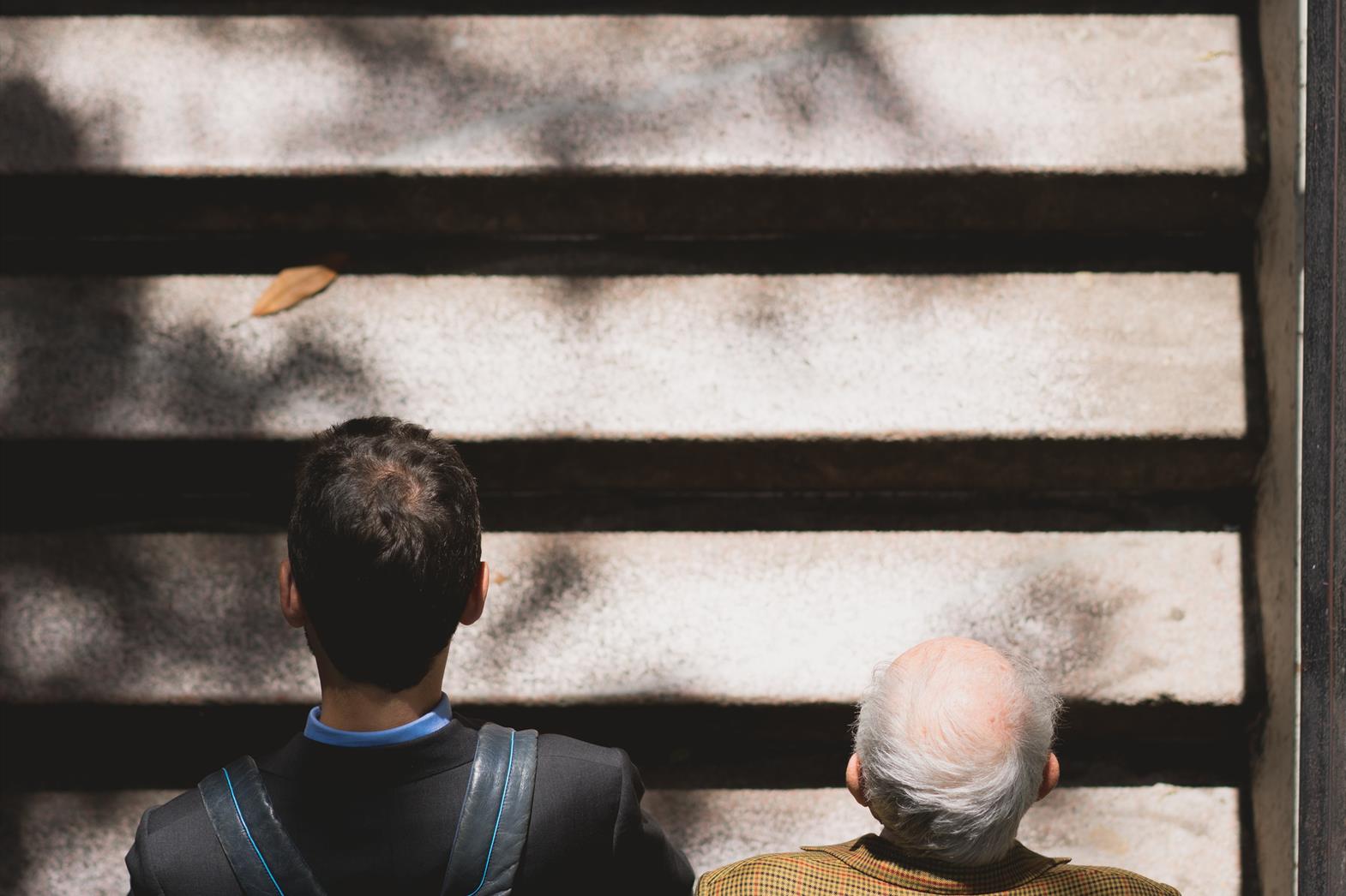 Photo of a young man and an elderly man climbing stairs