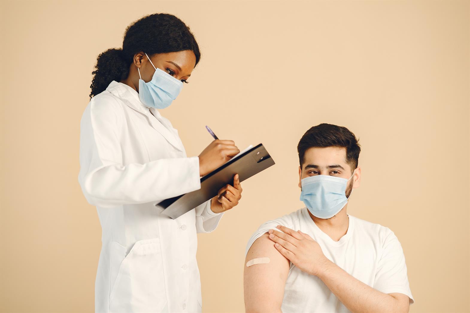 Un professionnel de santé portant un masque en train d'administrer un vaccin à un patient