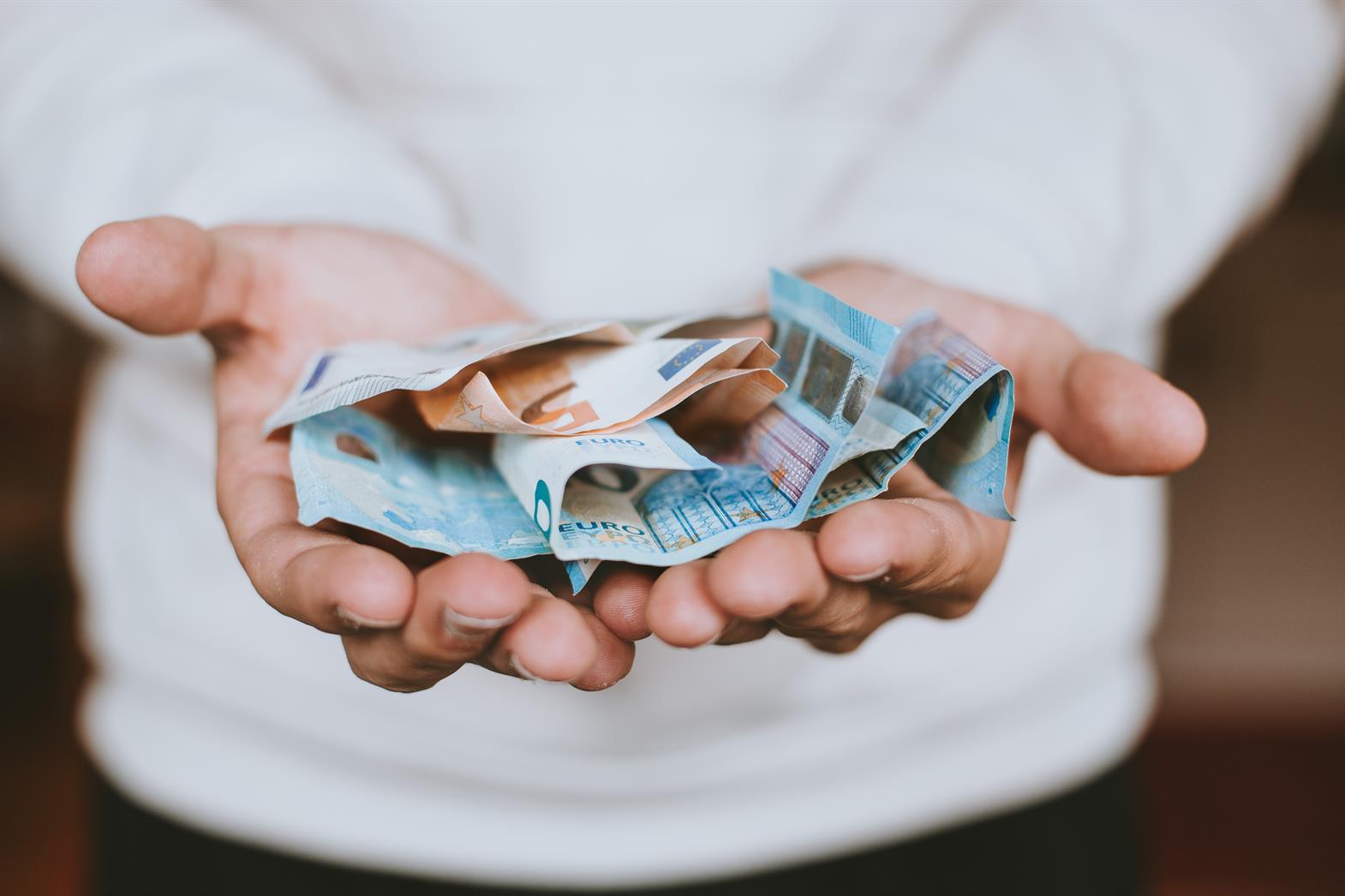 A person holding dollar bills in their hands